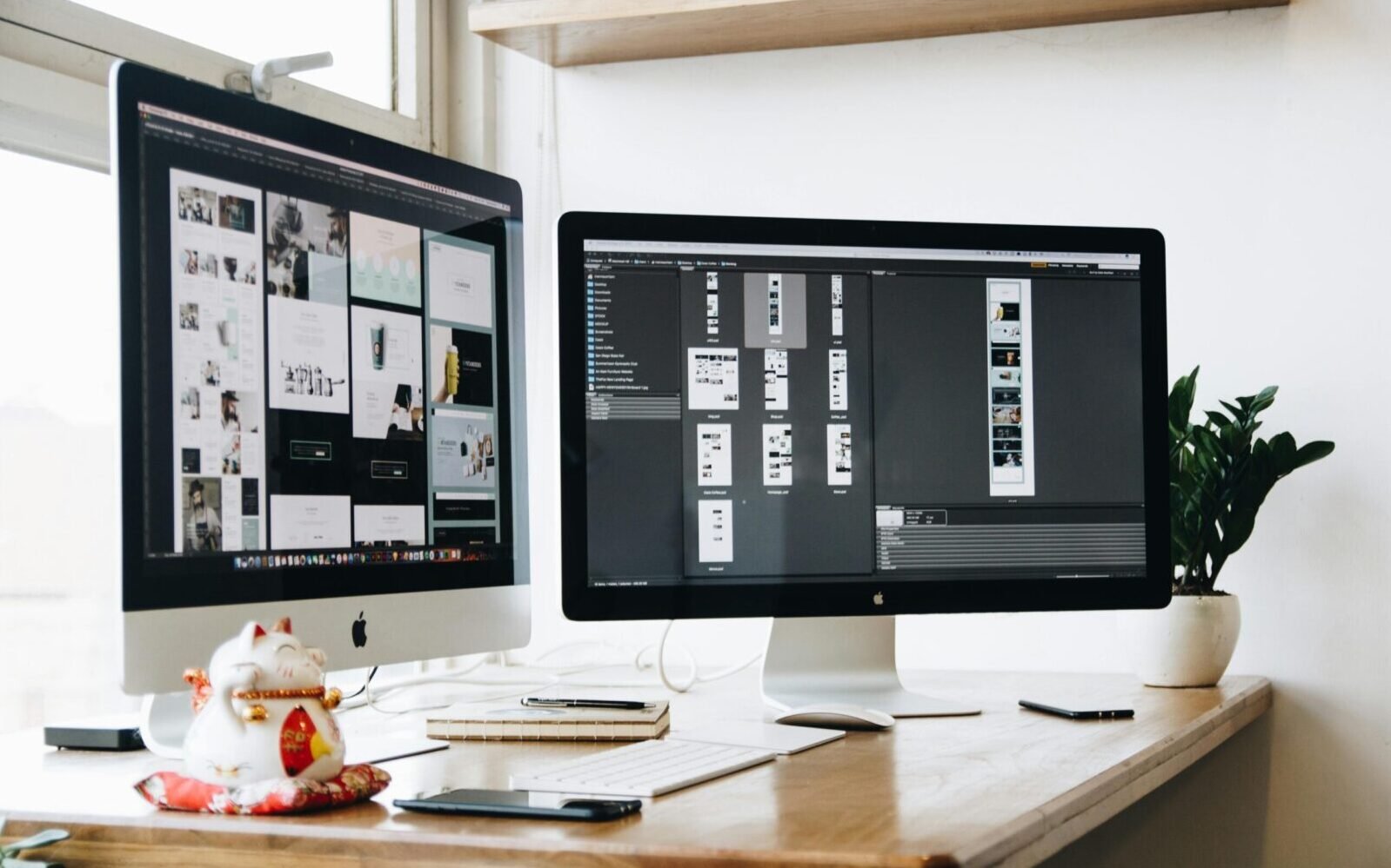 Stylish office workspace featuring dual monitors, a keyboard, notebooks, and decorative plant.